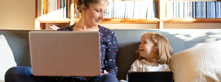 Woman using laptop daughter using iPad