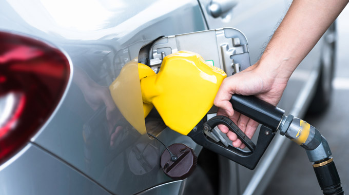 Yellow gas pump fueling silver car