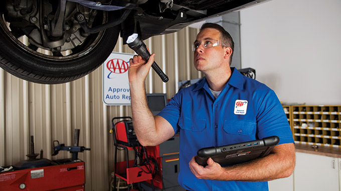 A AAA Approved Repair technician inspects the bottom of a car