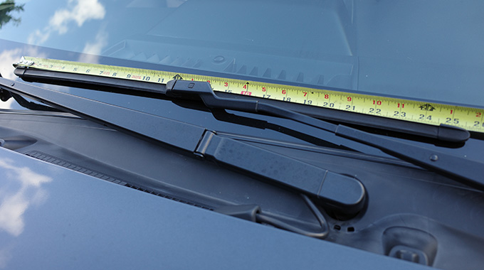 A tape measure laid on top of a windshield wiper blade