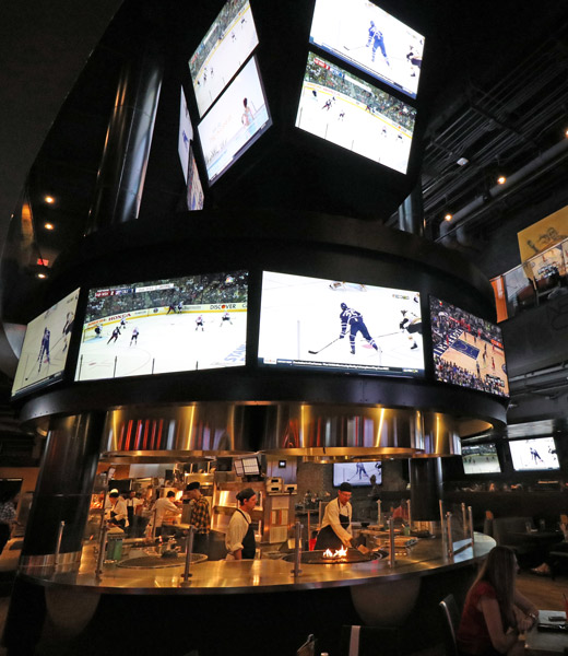 Interior of NBC Sports Grill & Brew showing the grill and many televisions