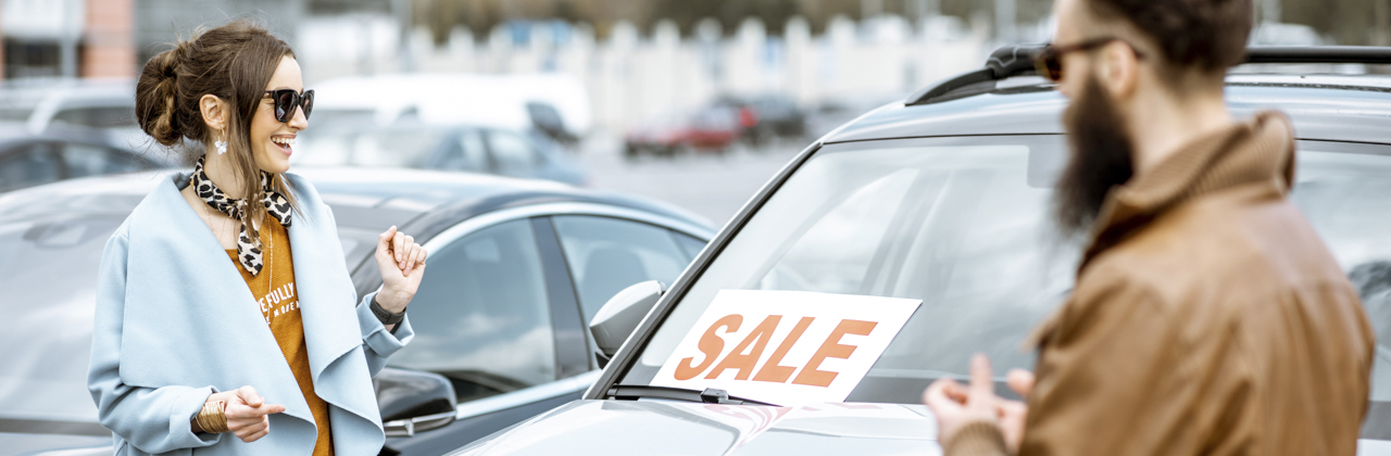Young stylish couple choosing luxury car to buy on the open ground of the dealership