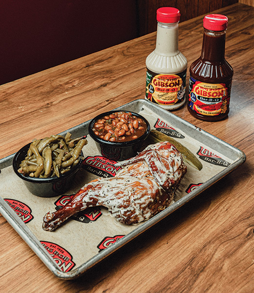 Big Bob Gibson BBQ tray with sides of green beans, baked beans, and extra sauce.