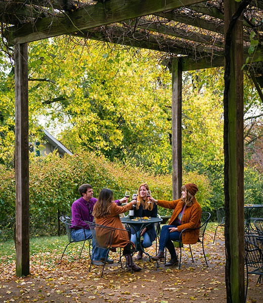 Group toasting wine glasses while seated outside at Augusta Winery.