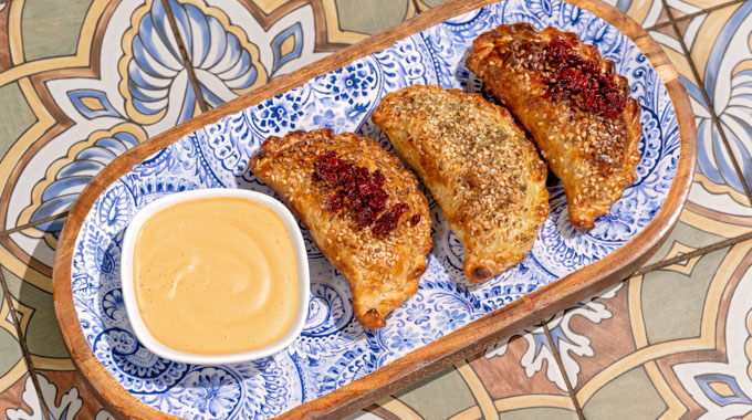 Trio of empanadas served with a dipping sauce.