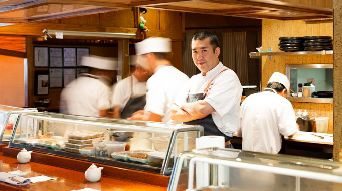 Chef Manabu "Hori" Horiuchi standing behind the sushi bar.