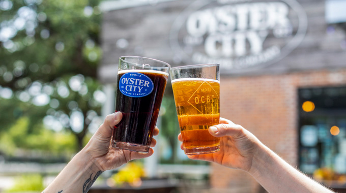 Two Oyster City Brewing Co. glasses being toasted together 