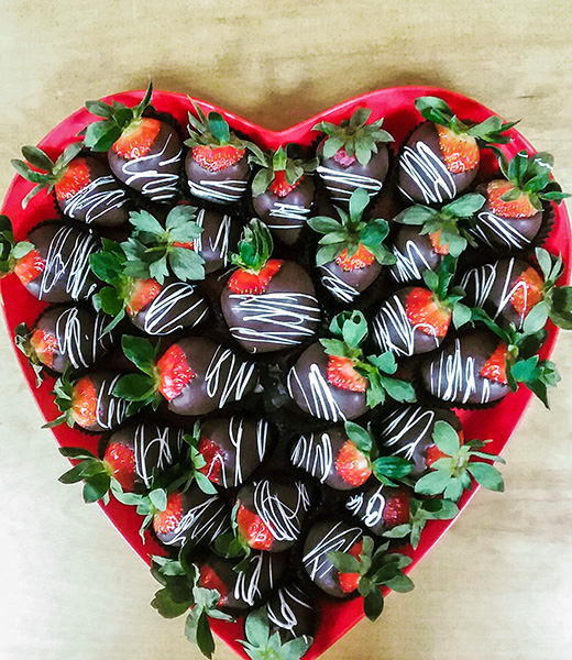 Chocolate-covered strawberries in a heart-shaped box.