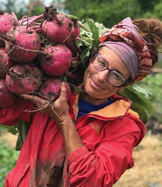 Woman shouldering a freshly harvested crop of beets.