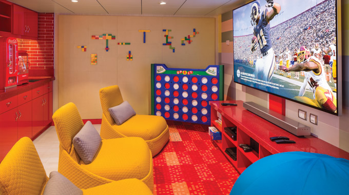 A game room with a large flat screen, jumbo Connect 4 set, and plush seating