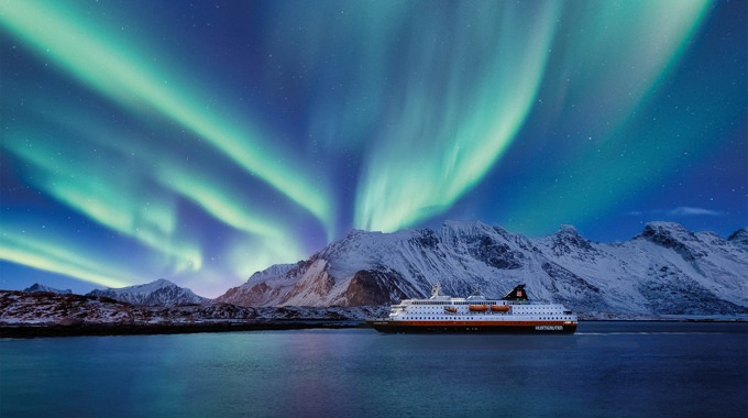Northen lights illuminating the sky above a cruise ship.