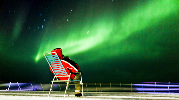 Person sitting on a cruise ship deck looking at the northern lights.