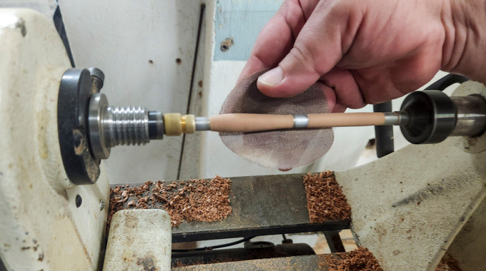 Someone using a wood turner to shape a pen.