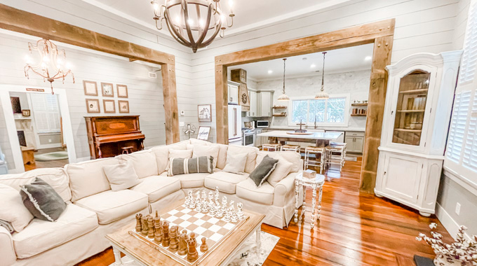 A chess set, cream couch, bookcase, and upright piano inside Magnolia Manor