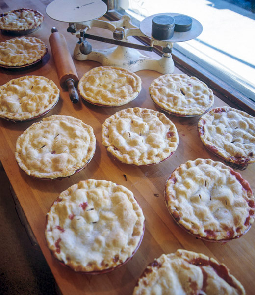 A table filled with apple pies in the making.