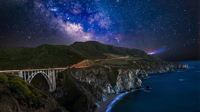 The Bixby Creek Bridge is lit up at night, but the Big Sur Coast Highway.