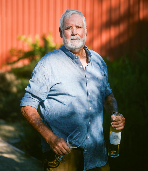 Bill Easton holding a wine glass and bottle.