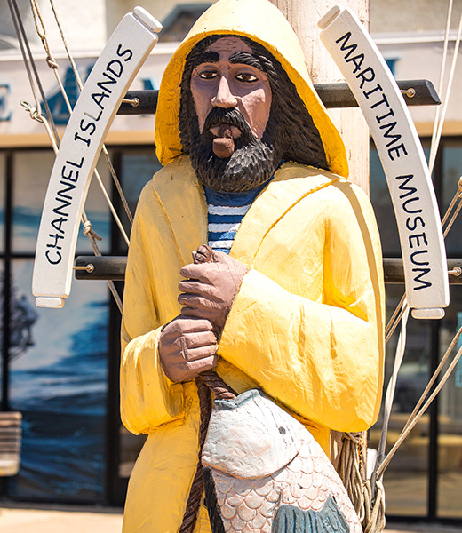 Statue of a fisherman in a yellow coat holding a large catch.