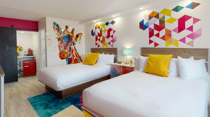 A room at Hotel Zazz with 2 beds and pops of color including geometric wall decals.