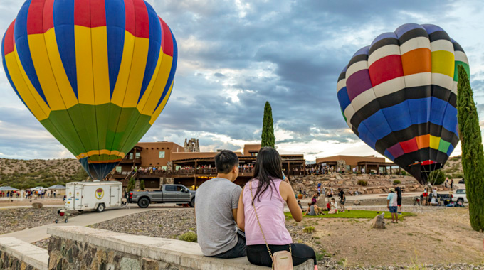 Couple facing toward hot air balloons preparing for flight