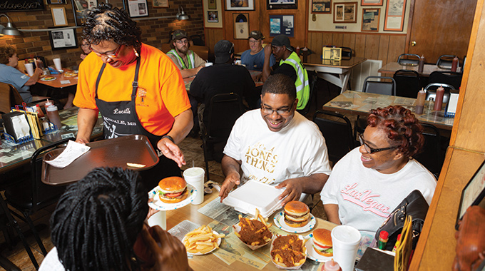 Diners enjoying burgers and chili fries at Abe’s Bar-B-Q.