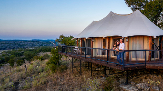 A couple enjoying the view from the deck of their luxury tent at Walden Retreats