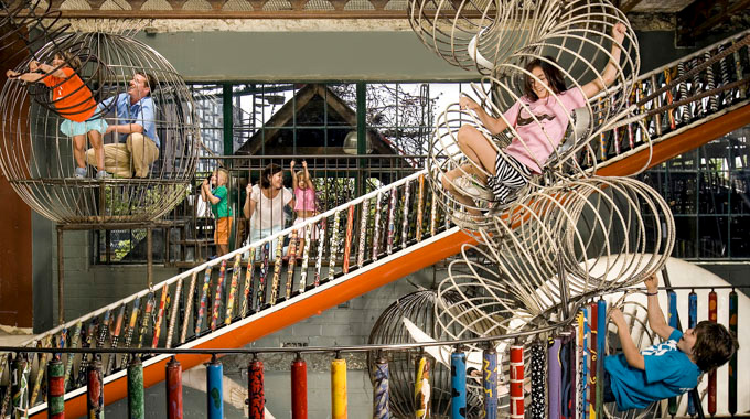 Museum visitors climbing giant slinky-shaped play structures
