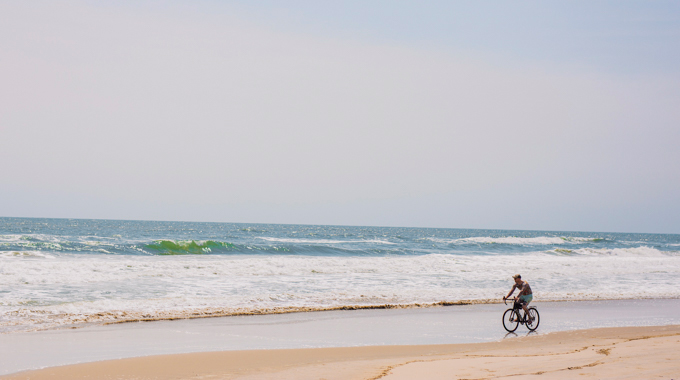 Bicyclist on shore of False Cape Beach.