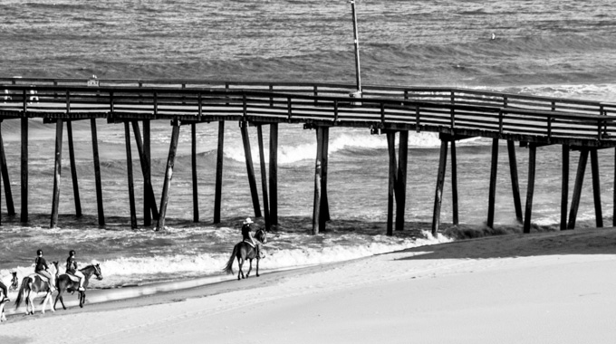 Group of riders on horseback on the Virginia Beach shoreline.