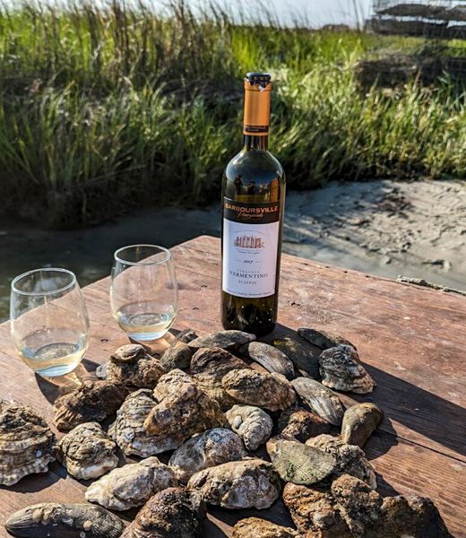 Pile of oysters served with a bottle of white wine.